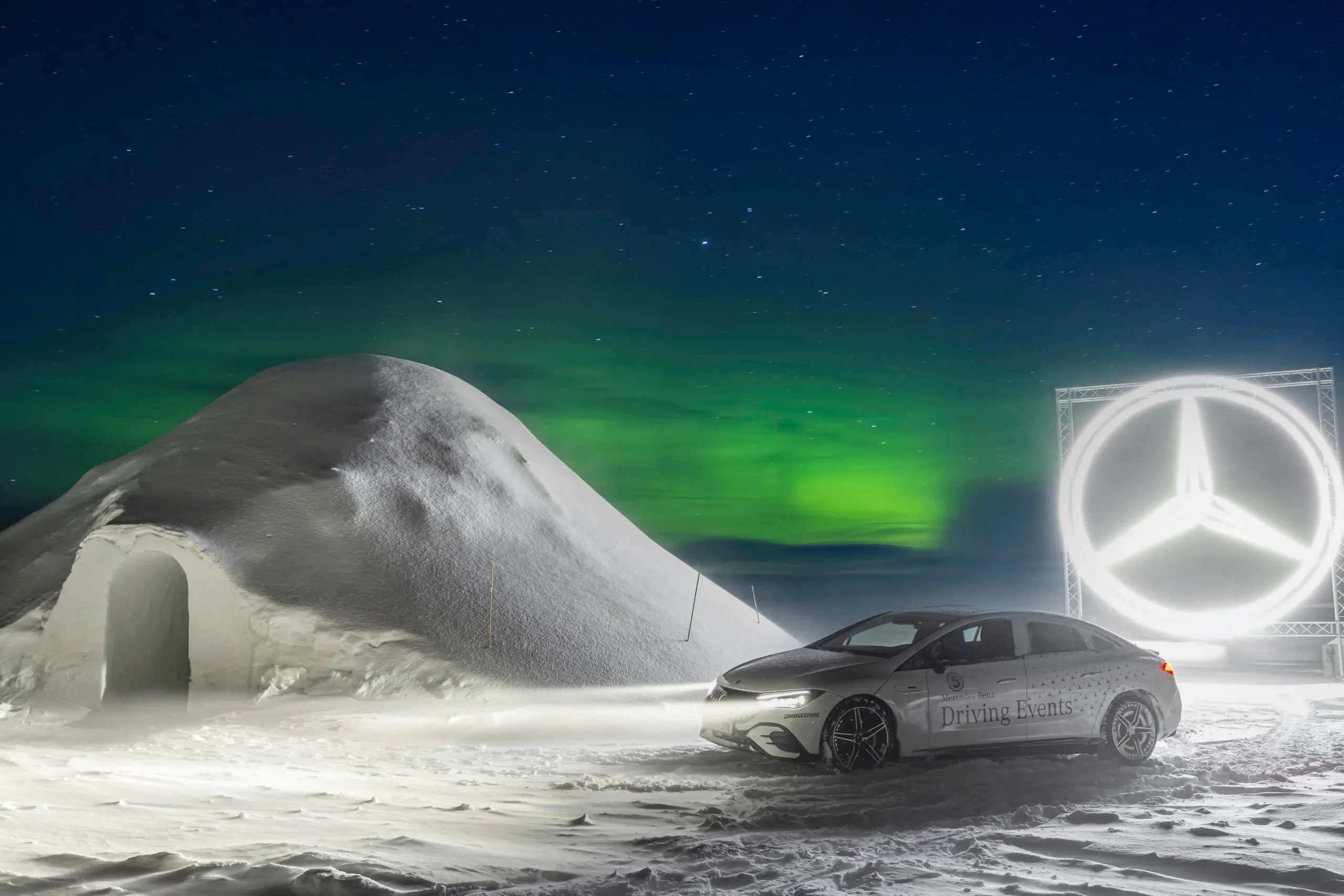 Fahrzeug vor einem Iglu unter Nordlichtern