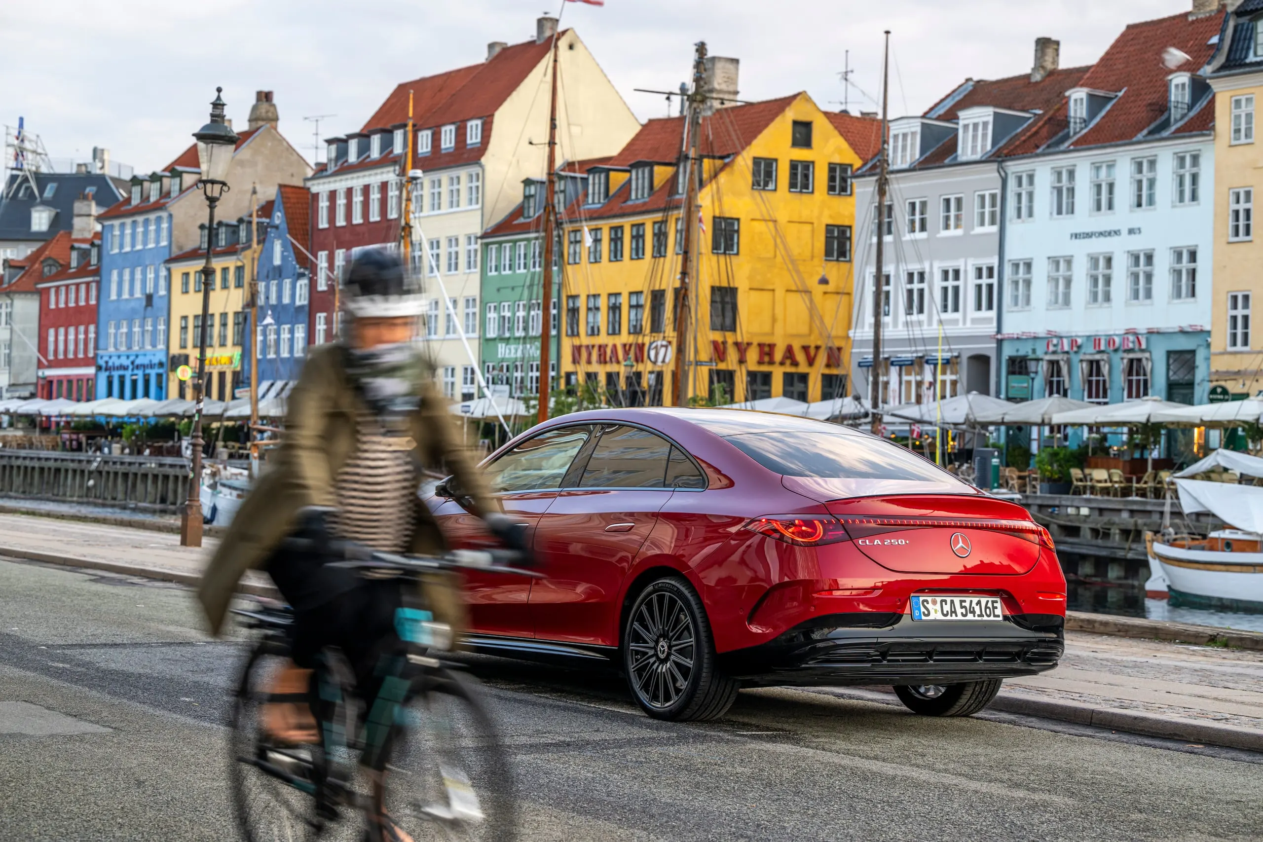 Radfahrerin fährt am roten CLA in Nyhavn vorbei