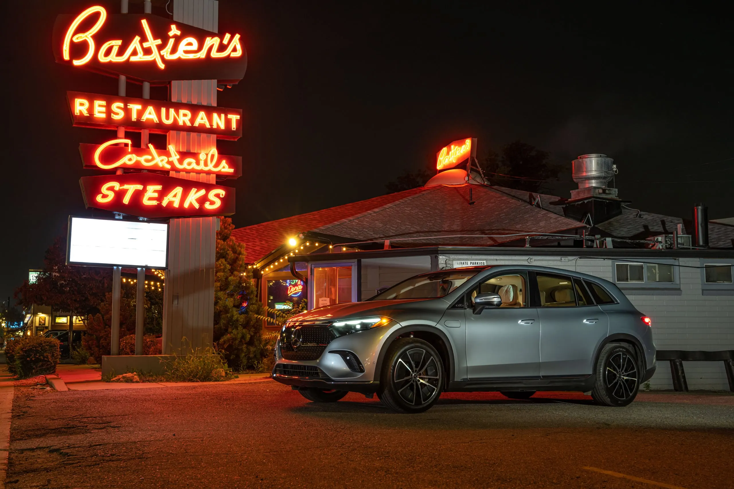 EQS SUV vor einem Steakhouse mit Leuchtreklame bei Nacht