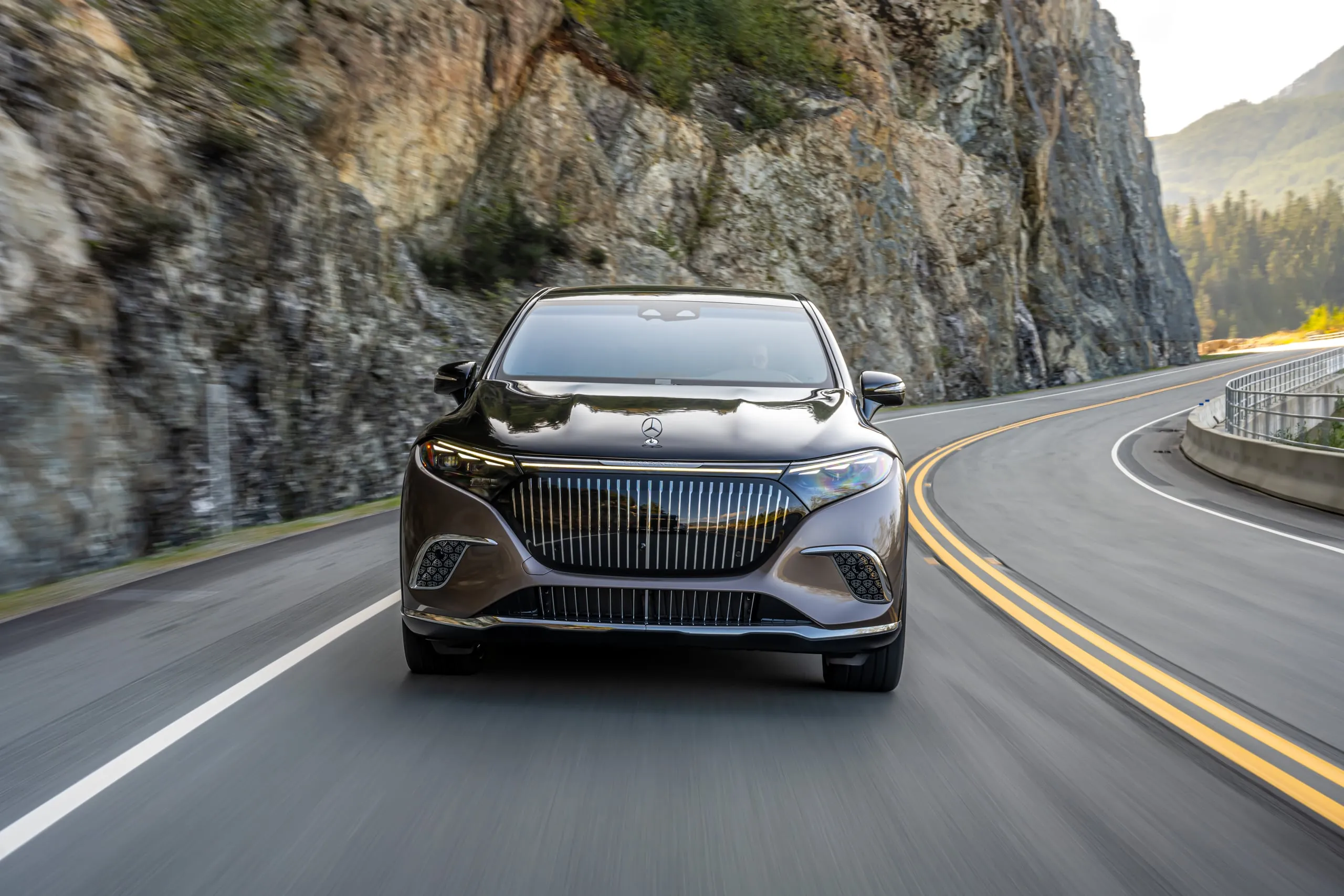 Maybach EQS SUV frontal in einer Kurve an einer Felswand