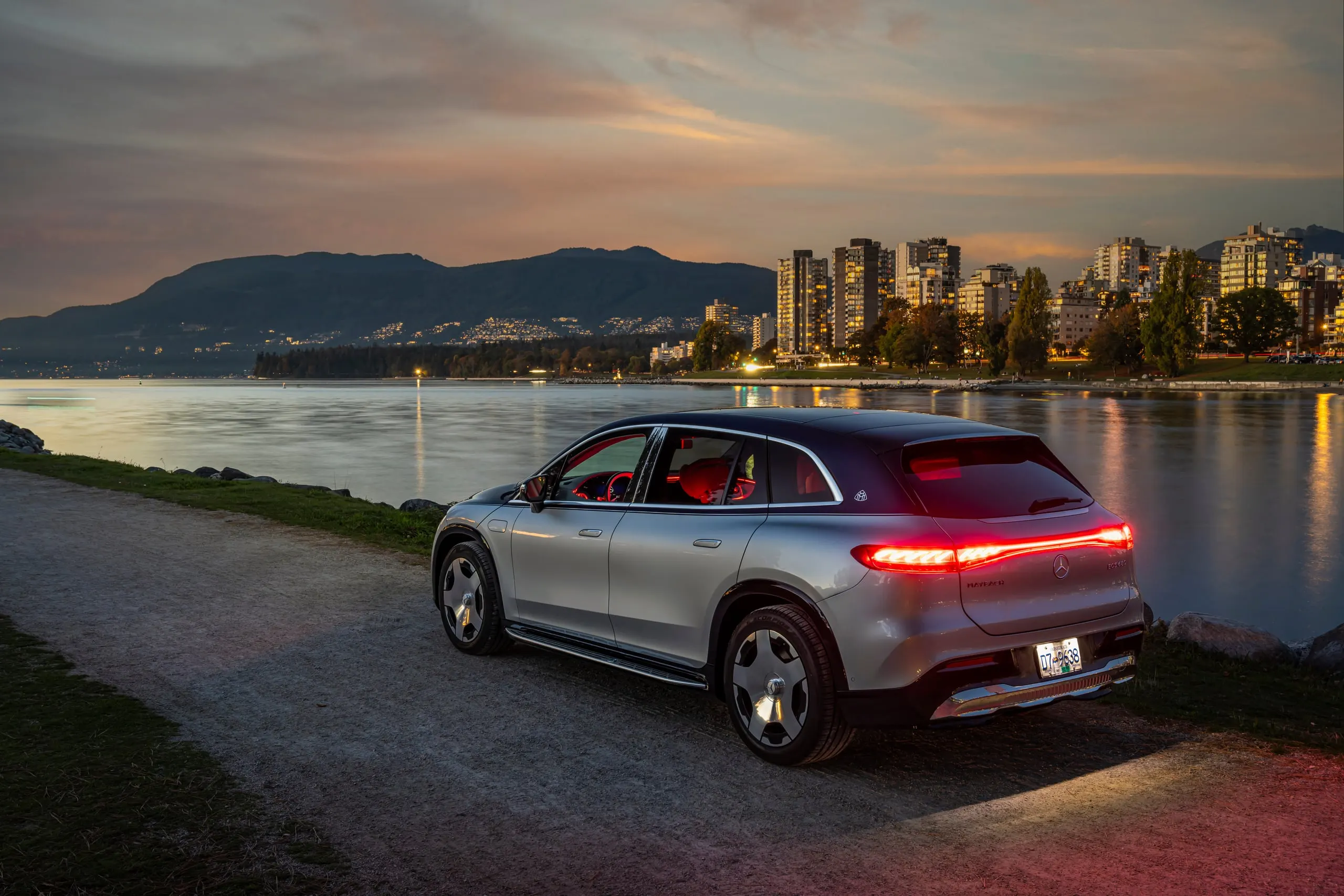 Maybach EQS SUV am Wasser vor der Stadt bei Abend