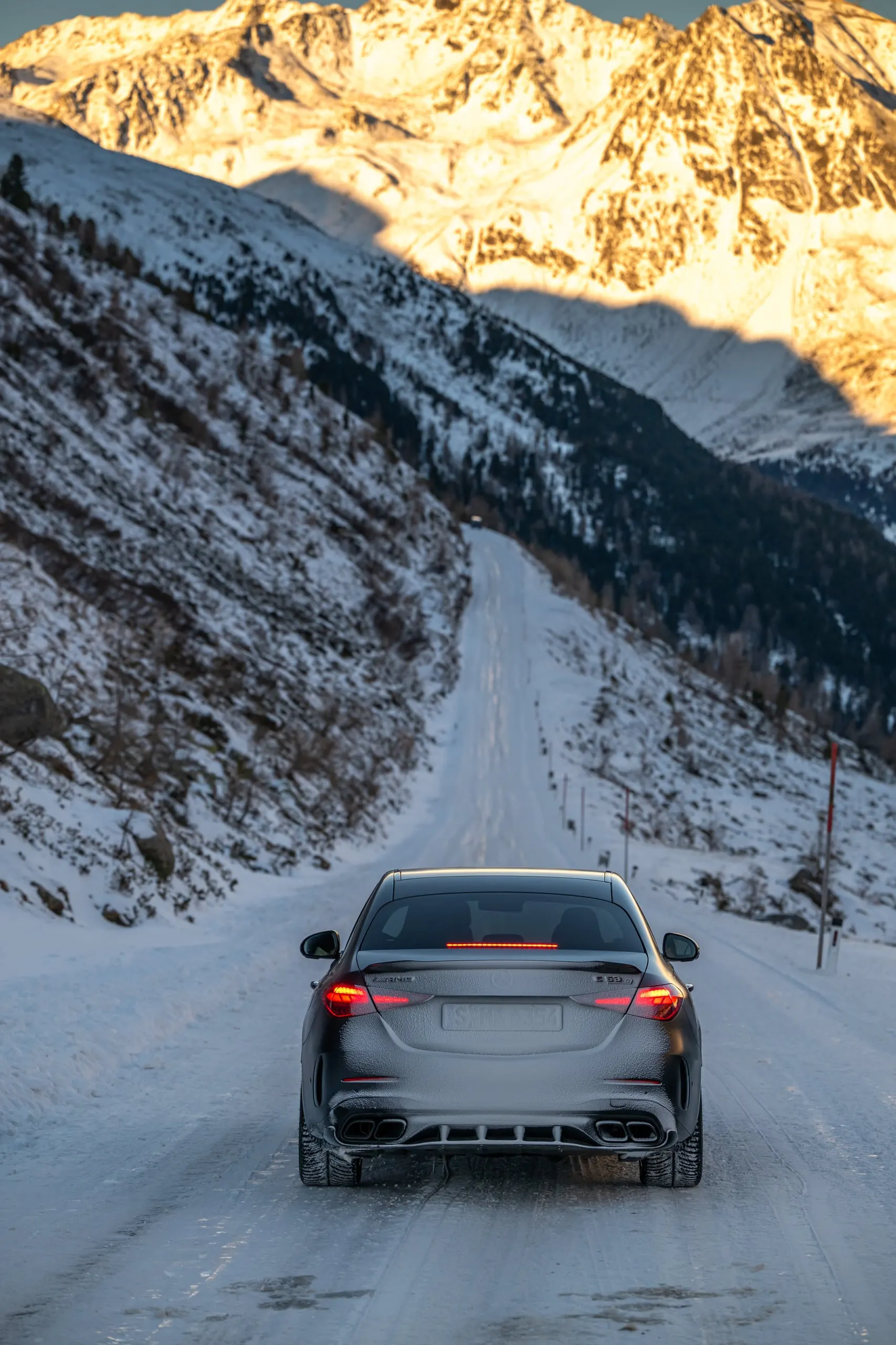 C 63 auf einer verschneiten Straße vor Bergen, Hochformat