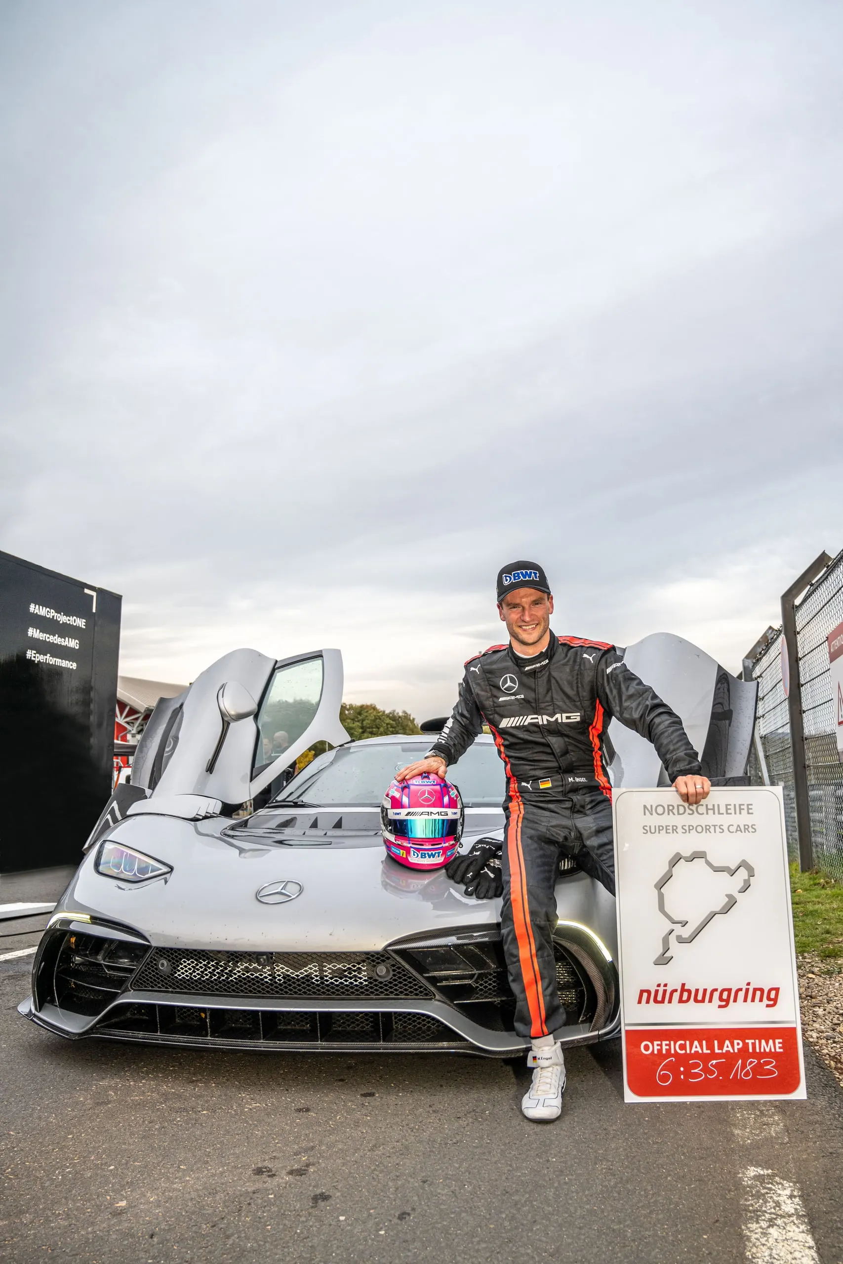Rennfahrer mit Rundenzeit-Tafel neben dem AMG ONE