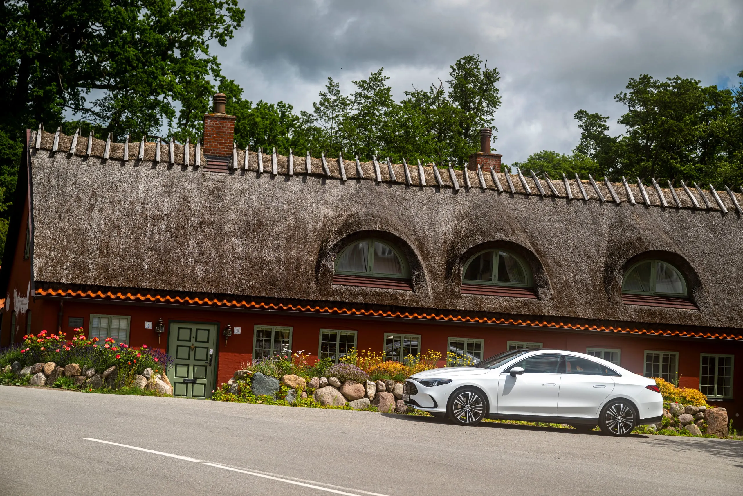 Weißer CLA vor einem reetgedeckten Haus