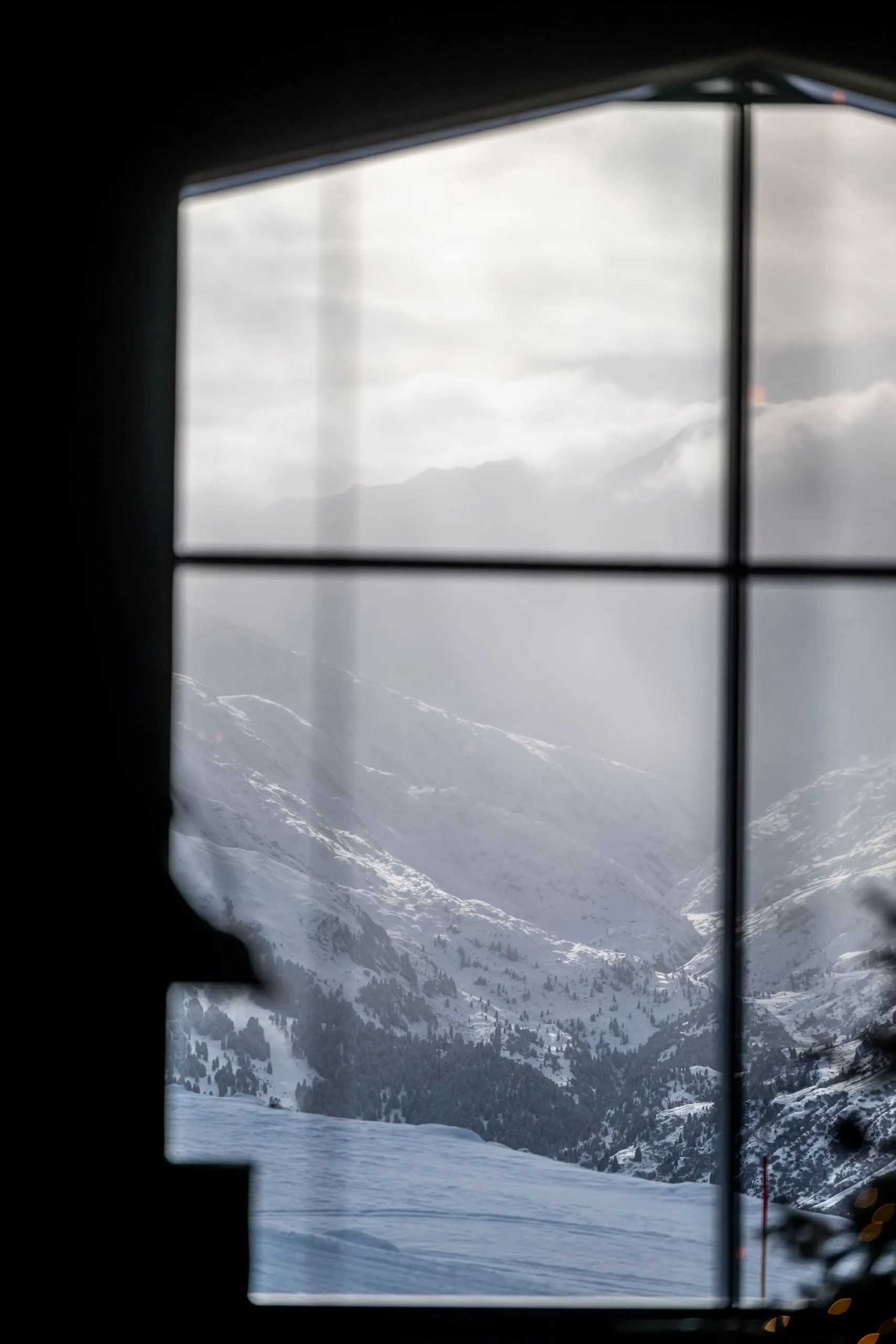 Blick durch ein Fenster auf verschneite Berge