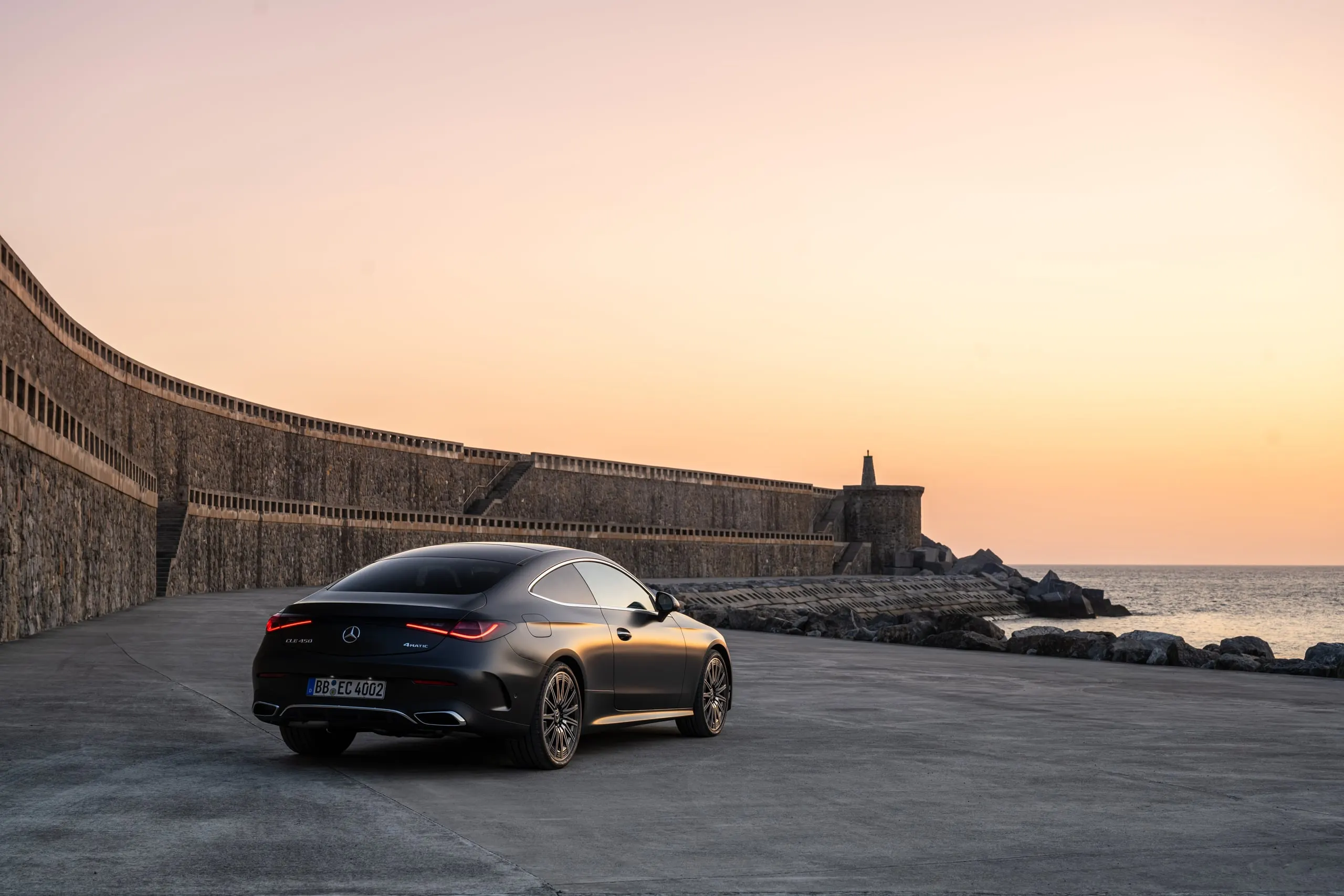 Graues CLE Coupé an einer Hafenmole bei Sonnenuntergang