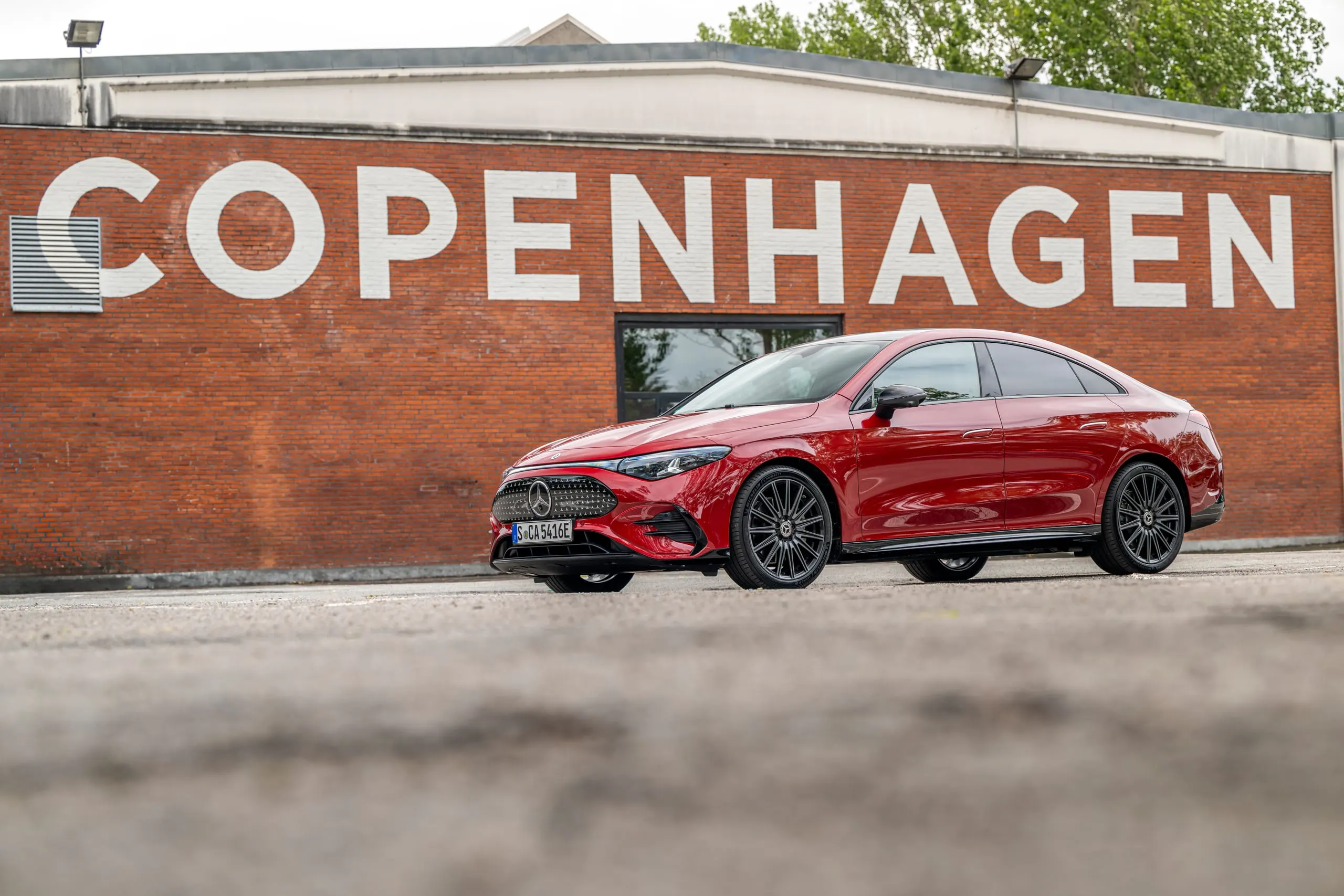 Roter CLA vor einer Backsteinwand mit Copenhagen-Schriftzug