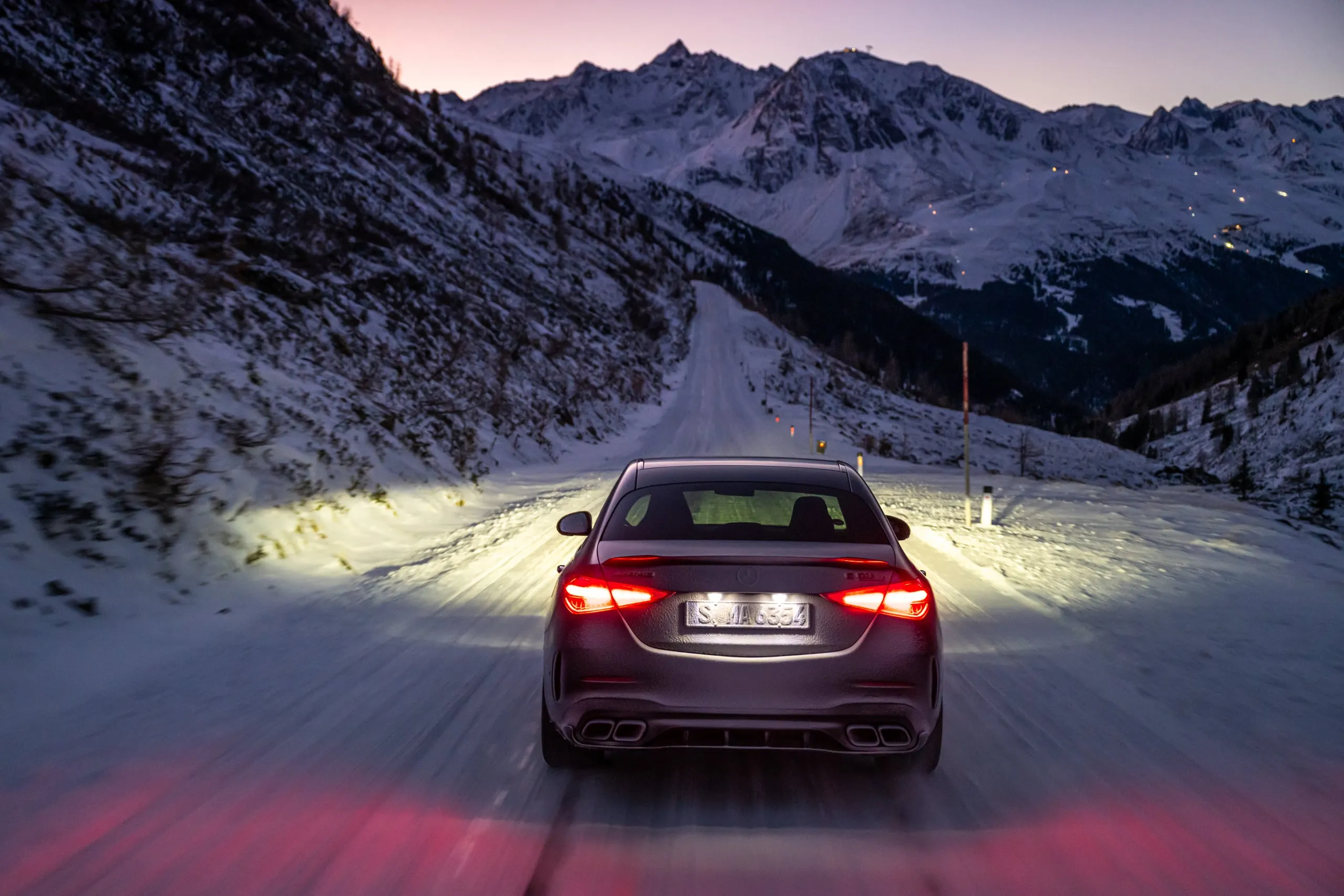 C 63 mit leuchtenden Rückleuchten auf einer verschneiten Straße