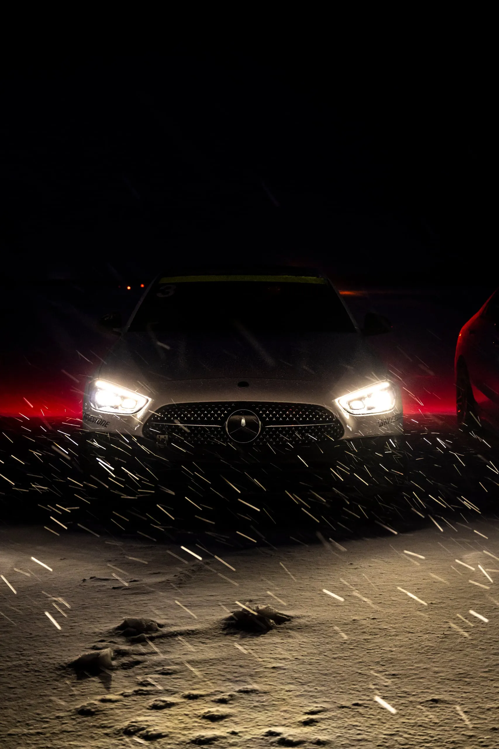 Scheinwerfer eines Fahrzeugs im Schneetreiben bei Nacht